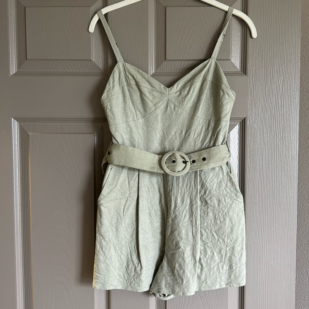 sage green linen romper. adjustable straps, belt, zipper back